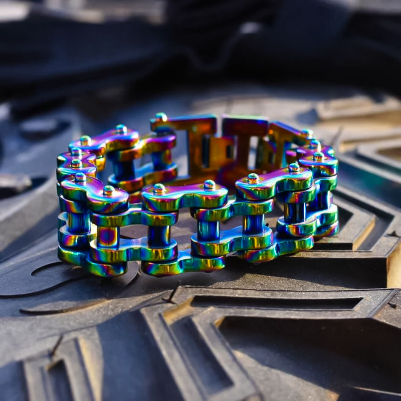 A multicolored vintage motorcycle chain bracelet laid out on a textured surface.