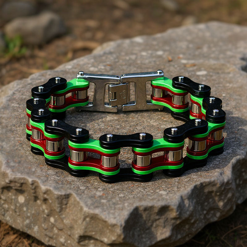Bracelet with green, red, and black links on a stone surface