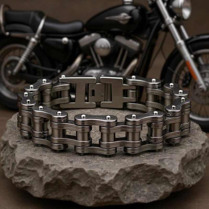 Metallic chain bracelet on a stone surface with a motorcycle in the background