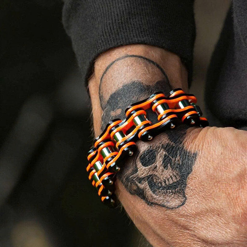 Bracelet with orange and black links on a wrist with tattoos