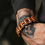 Bracelet with orange and black links on a wrist with tattoos