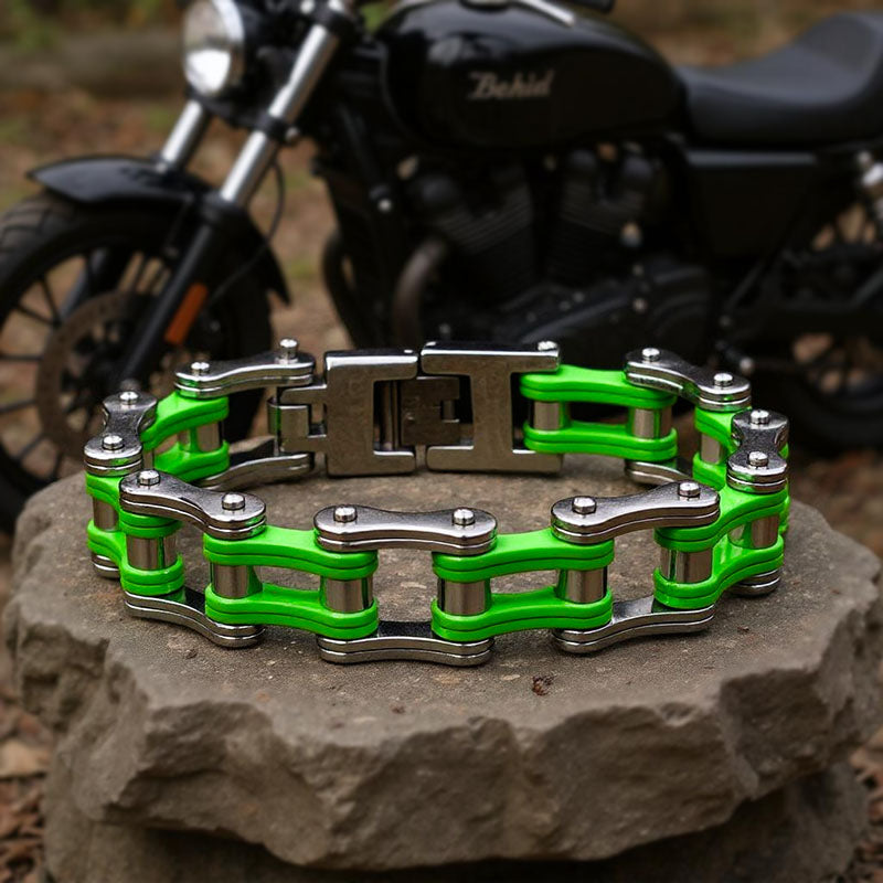Green and silver chain bracelet on a stone surface with a motorcycle in the background